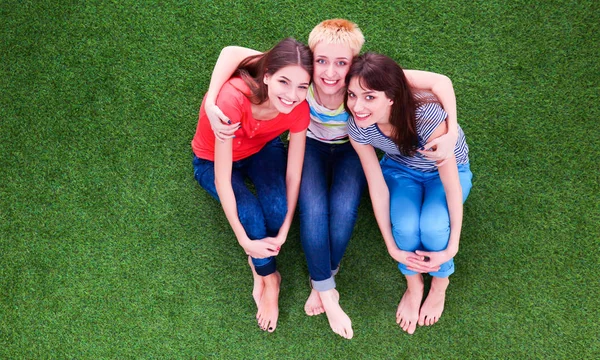 Drei entspannte schöne Flirterinnen sitzen auf grünem Gras — Stockfoto