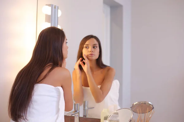 Atractiva joven que aplica crema en su cara — Foto de Stock