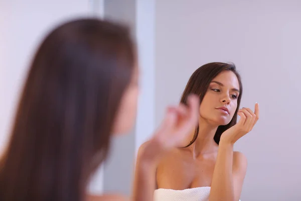 Attraktive junge Frau cremt ihr Gesicht ein — Stockfoto