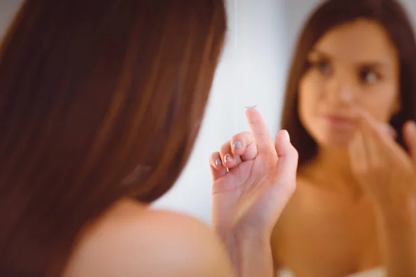 Atractiva joven que aplica crema en su cara — Foto de Stock