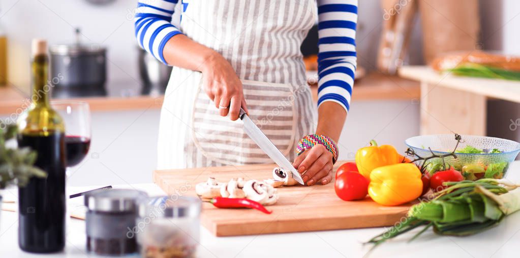 Young woman cutting vegetables in kitchen