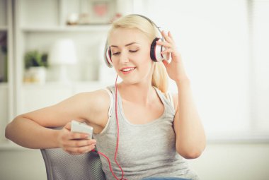 Evdeki genç ve güzel kadın kanepede oturup müzik dinliyor.