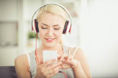 Evdeki genç ve güzel kadın kanepede oturup müzik dinliyor.