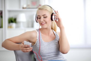 Evdeki genç ve güzel kadın kanepede oturup müzik dinliyor.