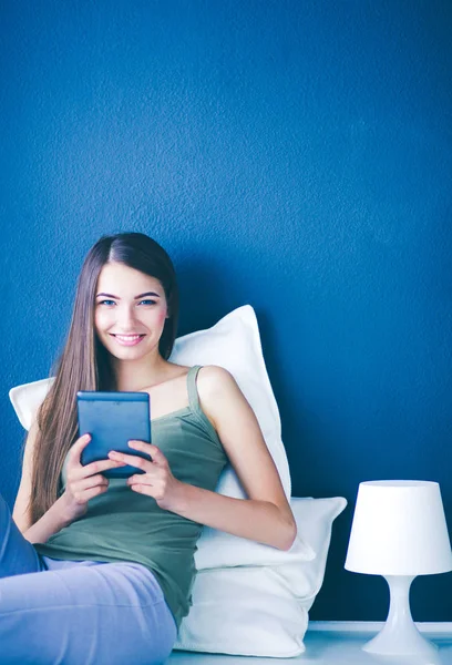 Mujer morena bonita sentada en el suelo con una almohada y mesa de avión — Foto de Stock