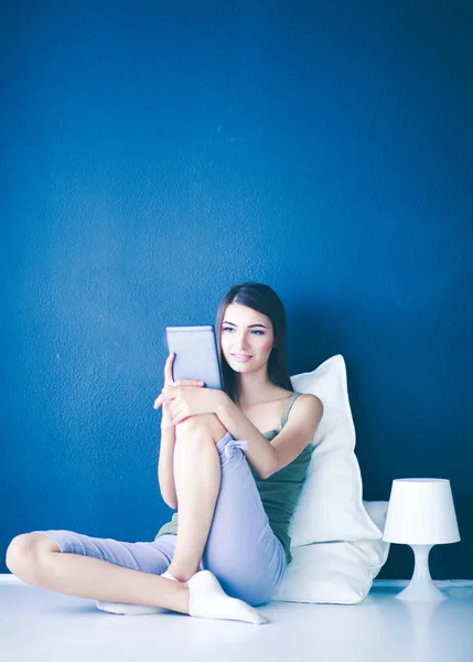 Pretty brunette woman sitting on the floor with a pillow and plane table — Stock Photo, Image