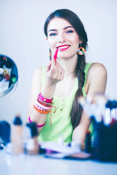 Giovane bella donna che fa il make-up vicino specchio, seduto alla scrivania — Foto Stock