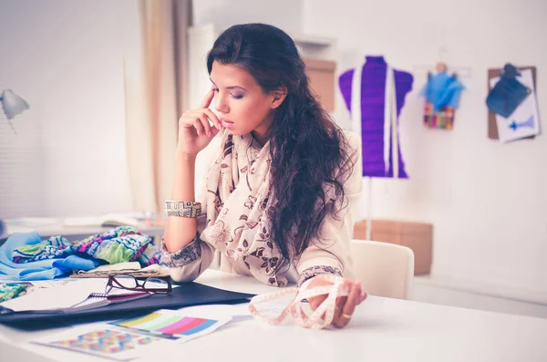 Glimlachende vrouwelijke mode-ontwerper zit aan het bureau — Stockfoto