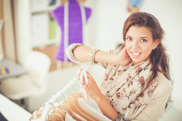 Mooie jonge stylist vrouw in de buurt van rack met hangers — Stockfoto