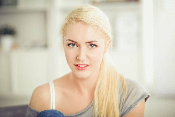 Молодая красивая женщина сидит на диване в своей комнате