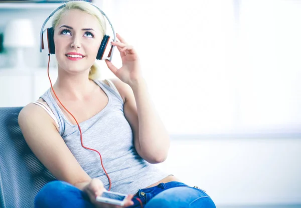 Joven hermosa mujer en casa sentada en el sofá y escuchando música — Foto de Stock