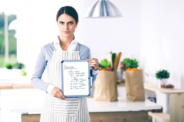 Kobieta w kuchni w domu, stojąca przy biurku z folderem — Zdjęcie stockowe