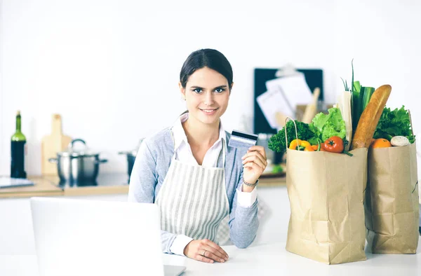 Donna sorridente shopping online con computer e carta di credito in cucina — Foto Stock