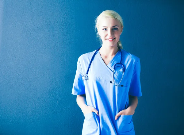 Portret uśmiechający się lekarza w jednolite stojący na szarym tle — Zdjęcie stockowe