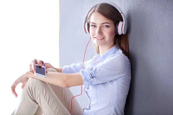 Jovem menina feliz sentado no chão e ouvir música — Fotografia de Stock