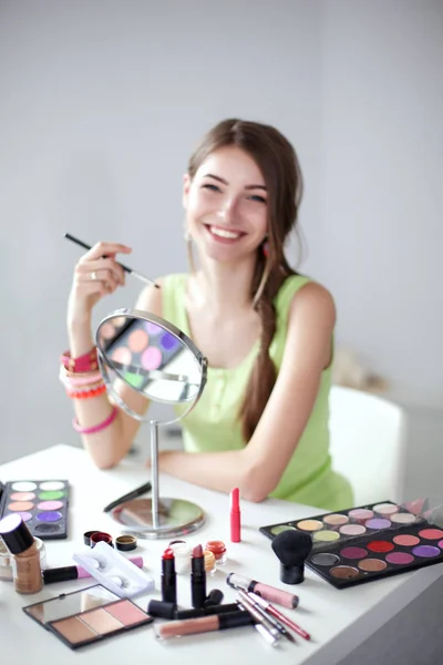 Genç güzel kadın ayna, Masa başında oturan yakınındaki makyaj yapma — Stok fotoğraf
