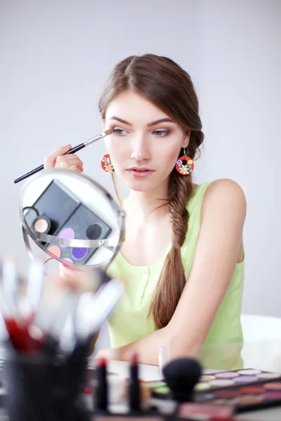 Όμορφη κοπέλα κάνοντας make-up κοντά καθρέφτη, κάθεται στο γραφείο — Φωτογραφία Αρχείου