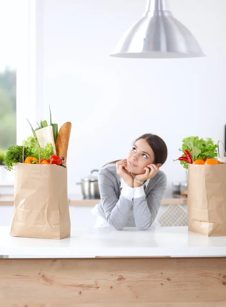 Young woman holding grocery shopping bag with vegetables . Standing in the kitchen — Stock Photo, Image