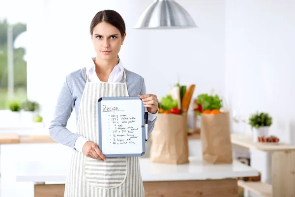 Femme dans la cuisine à la maison, debout près du bureau avec dossier — Photo