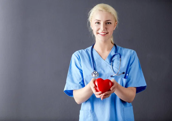 Молодая женщина-врач со стетоскопом держит сердце — стоковое фото