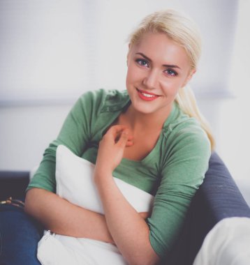 Genç ve güzel bir kadın odasında kanepede oturuyor.