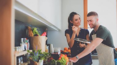 Bir çift evdeki mutfaklarında birlikte yemek pişiriyor.
