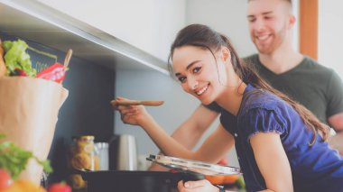 Bir çift evdeki mutfaklarında birlikte yemek pişiriyor.