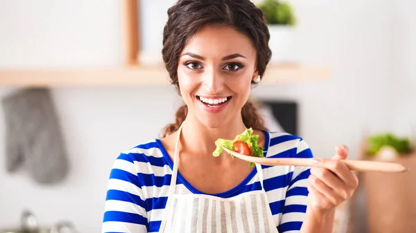 Fiatal nő eszik friss salátát a modern konyhában — Stock Fotó