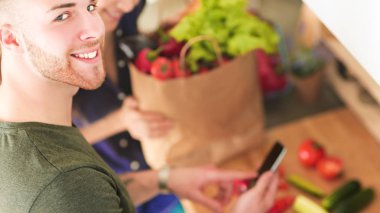 Mutlu çift Smartphone ayakta mutfakta kullanarak