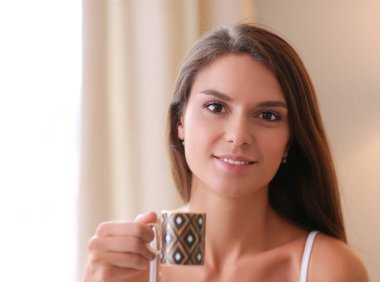 bir bardak süt ile yatakta oturan genç kadın