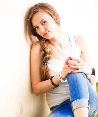 Katta oturan ve bir fincan tutan güzel bir kadın. Güzel kadın