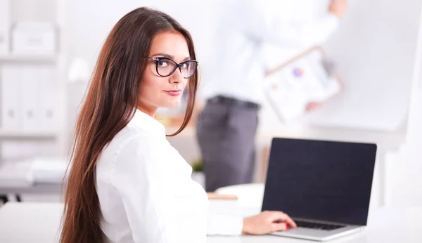 Una atractiva mujer de negocios sentada en la oficina, en el escritorio. Atractiva mujer de negocios —  Fotos de Stock