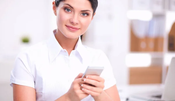 Businesswoman sending message with smartphone sitting in the office — Stock Photo, Image