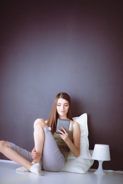 bir yastık ve uçak tablo ile katta oturan güzel esmer kadın