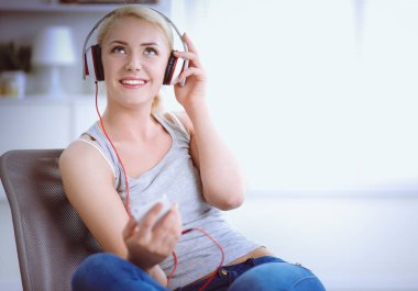 Evdeki genç ve güzel kadın kanepede oturup müzik dinliyor.