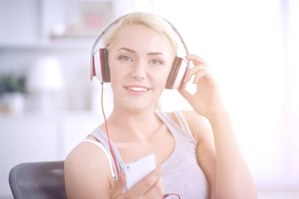 Jeune belle femme à la maison assise sur un canapé et écoutant de la musique — Photo