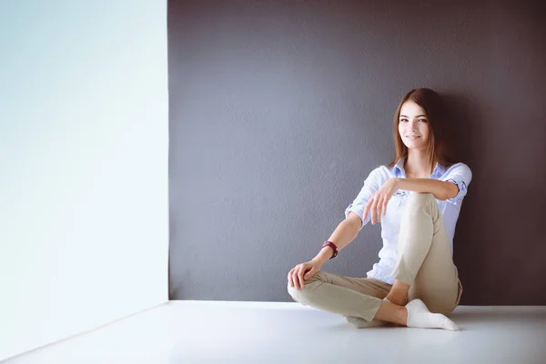 Jovem mulher sentada no chão perto da parede escura — Fotografia de Stock