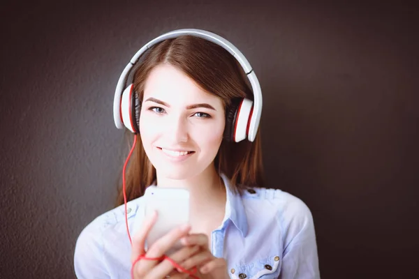 Joven chica feliz sentada en el suelo y escuchando música — Foto de Stock