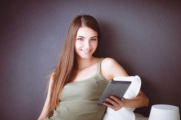 Mujer morena bonita sentada en el suelo con una almohada y mesa de avión — Foto de Stock