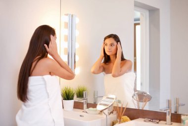 Çekici genç bir kadın yüzüne krem sürüyor.