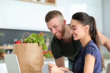 Çift evde mutfak içinde laptop ile onların fatura ödeme