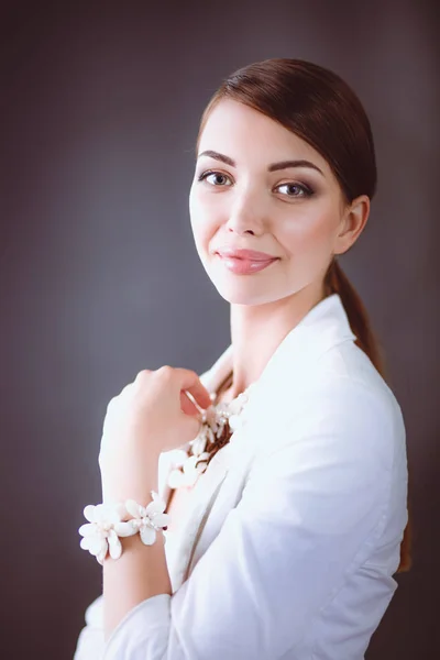 Portrait of young woman with beads, standing on gray background — Stock Photo, Image