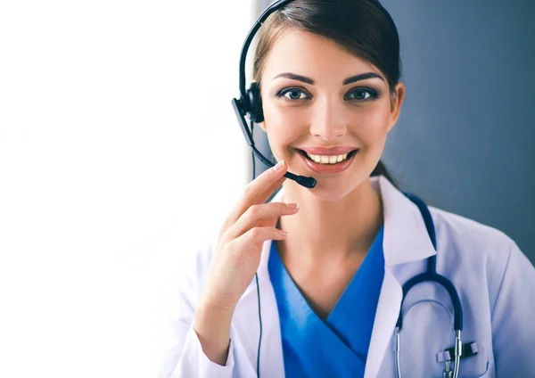 Lekarz w słuchawkach siedzi za biurkiem z laptopem — Zdjęcie stockowe