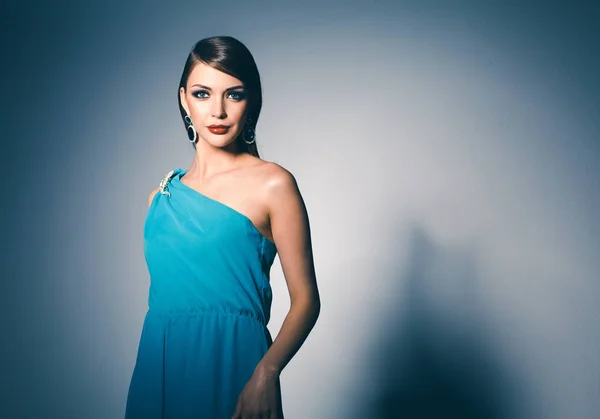 Jovem mulher bonita com cabelos longos posando em vestido de noite azul — Fotografia de Stock