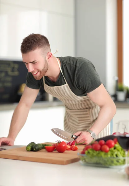 Masadaki dizüstü bilgisayara bakarken mutfakta sebze pişiren adamın portresi. — Stok fotoğraf