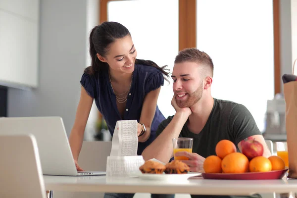 Ehepaar bezahlt seine Rechnungen mit Laptop in der heimischen Küche — Stockfoto