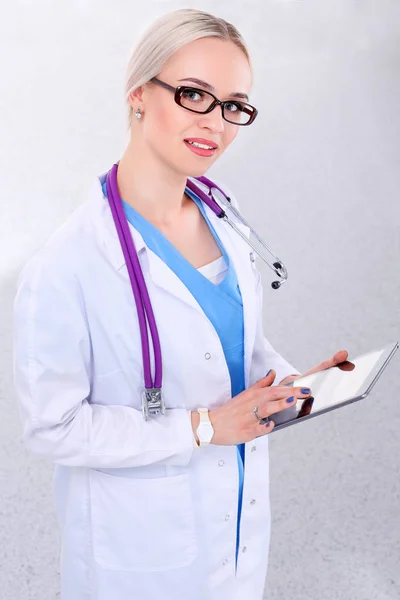 Médica usando um comprimido digital e de pé sobre fundo branco. Mulheres médicas. — Fotografia de Stock