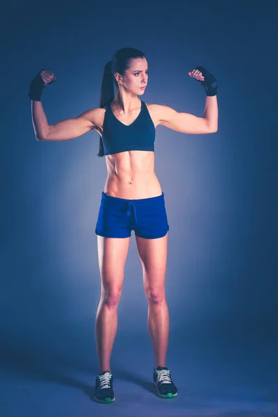 Gespierde jonge vrouw poseren in sportkleding tegen zwarte achtergrond. — Stockfoto