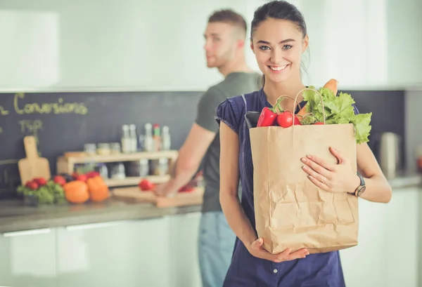 Mutfakta genç bir çift, alışveriş torbası taşıyan bir kadın. — Stok fotoğraf