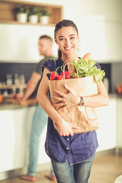 Jong stel in de keuken, vrouw met een zak boodschappen doen — Stockfoto